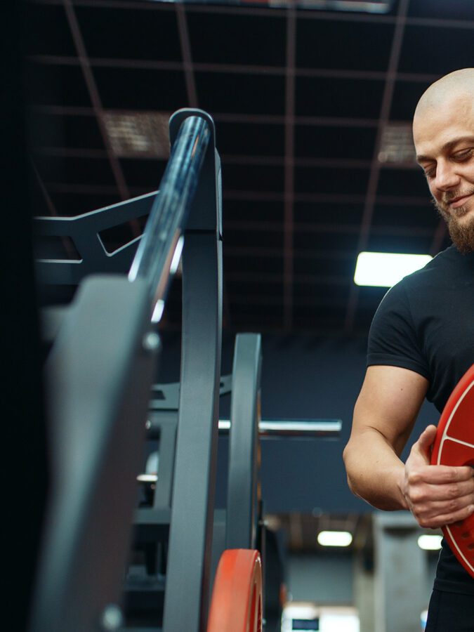 Personal trainer putting weights on barbell