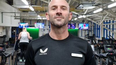 A man standing in a gym with his hands behind his back