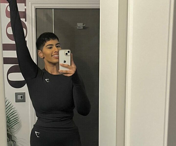 A woman standing in a doorway in exercise clothes